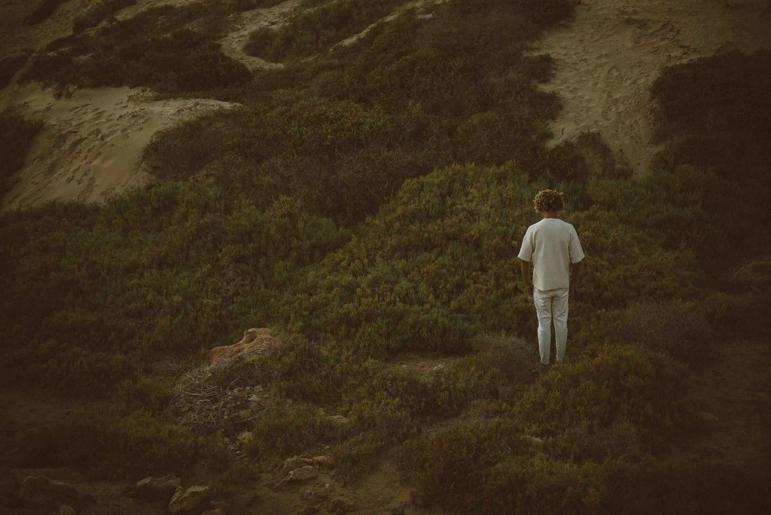 Man in white clothes standing alone on a hillside