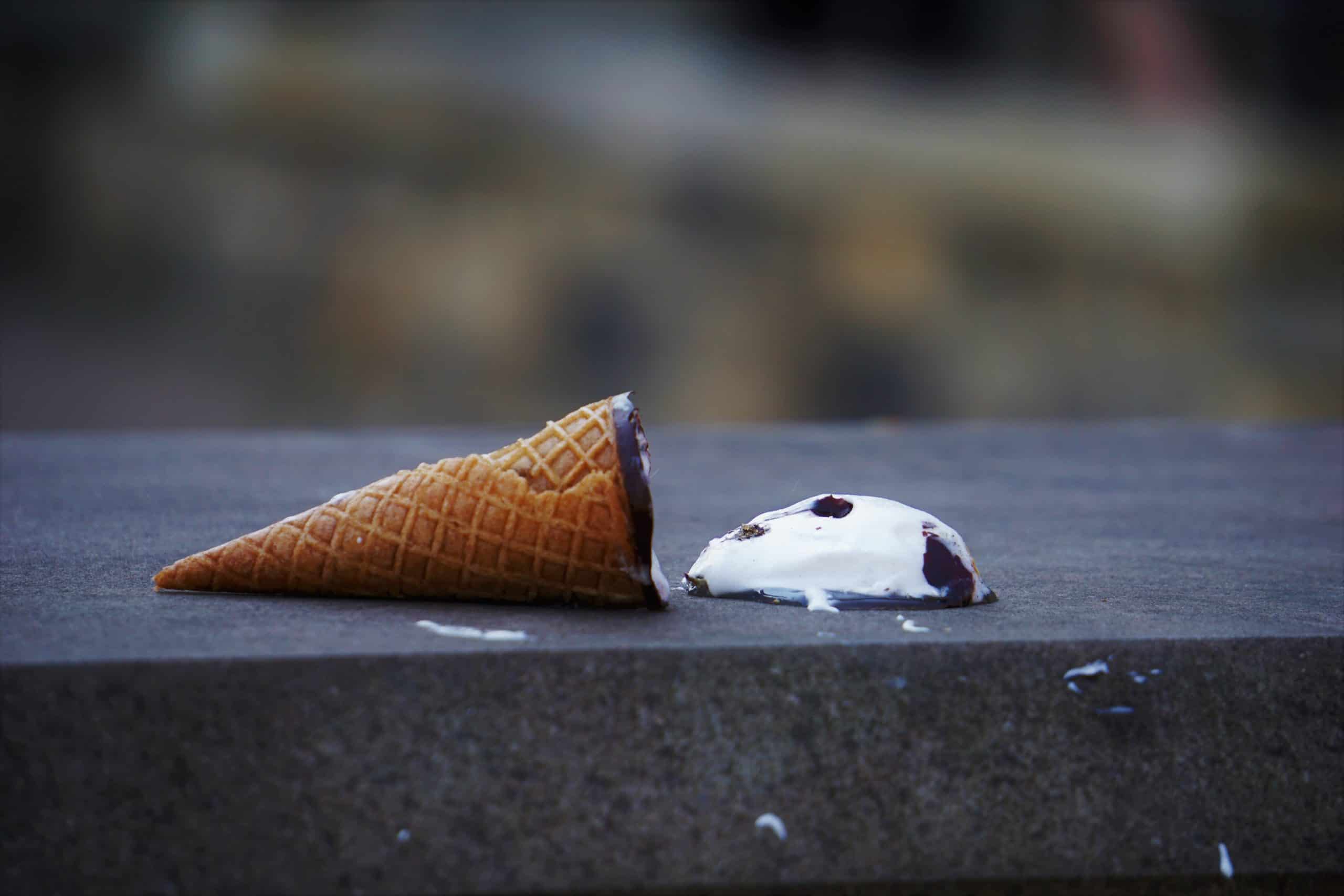 a tipped over ice cream cone with the ice cream spilt